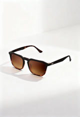 Twig Roth unisex square sunglasses in black frame with brown gradient UV3 lenses, displayed on a white surface under natural light.