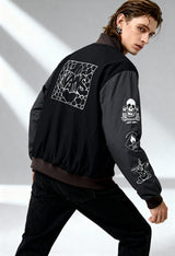 Man wearing Vans VN000JY1KOU1 black bomber jacket showing sleeve graphics and back artwork in studio light.