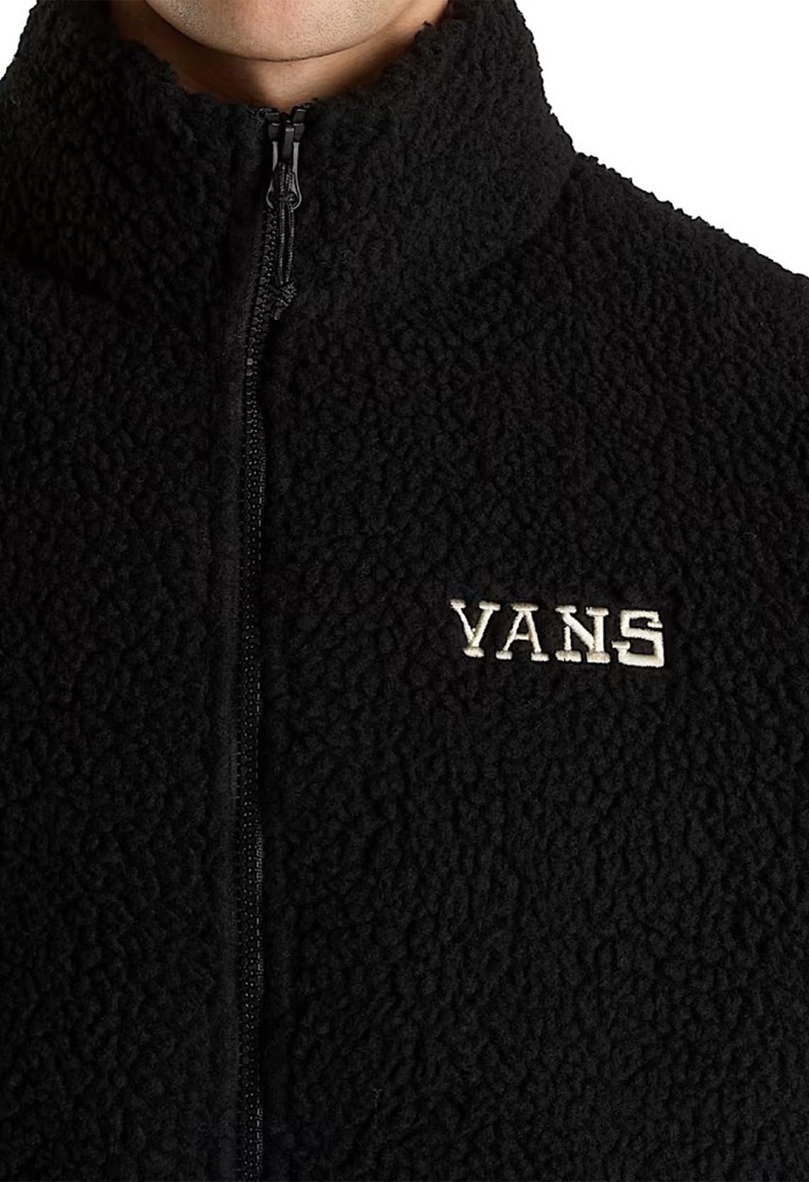 Close-up of Vans VN000NDUBLK1 fleece jacket showing textured fabric and embroidered Vans logo on chest.