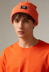Male model wearing Vans VN0A5GPLQID1 orange unisex beanie hat with fold-over cuff and Vans logo patch.