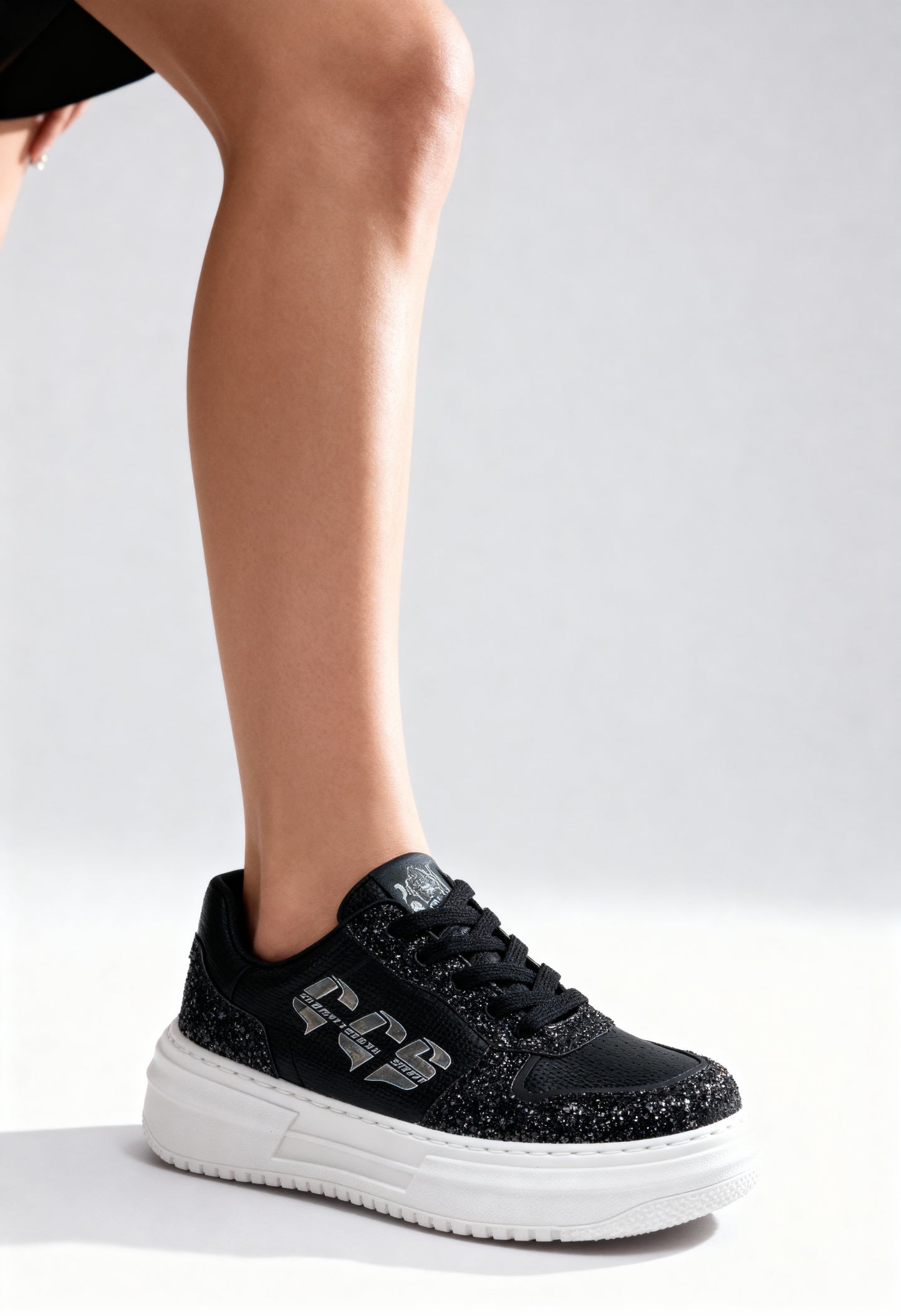 On-foot view of the black Cavalli Class platform sneakers with glitter detailing and white sole.