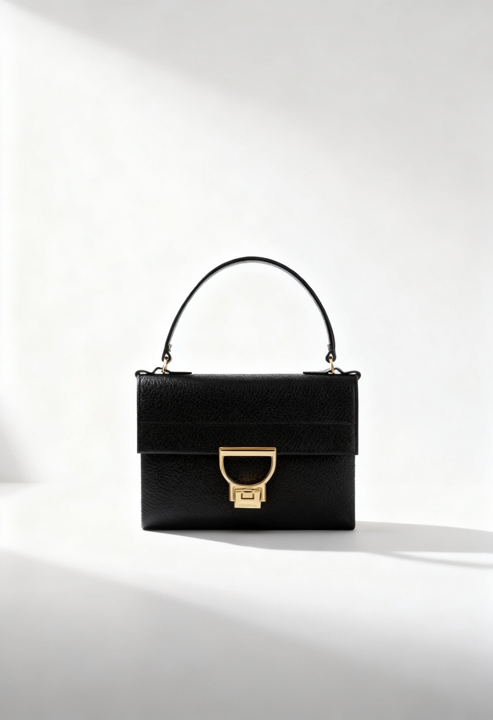 Brand new Coccinelle Arlettis Mini black leather handbag with gold buckle closure.