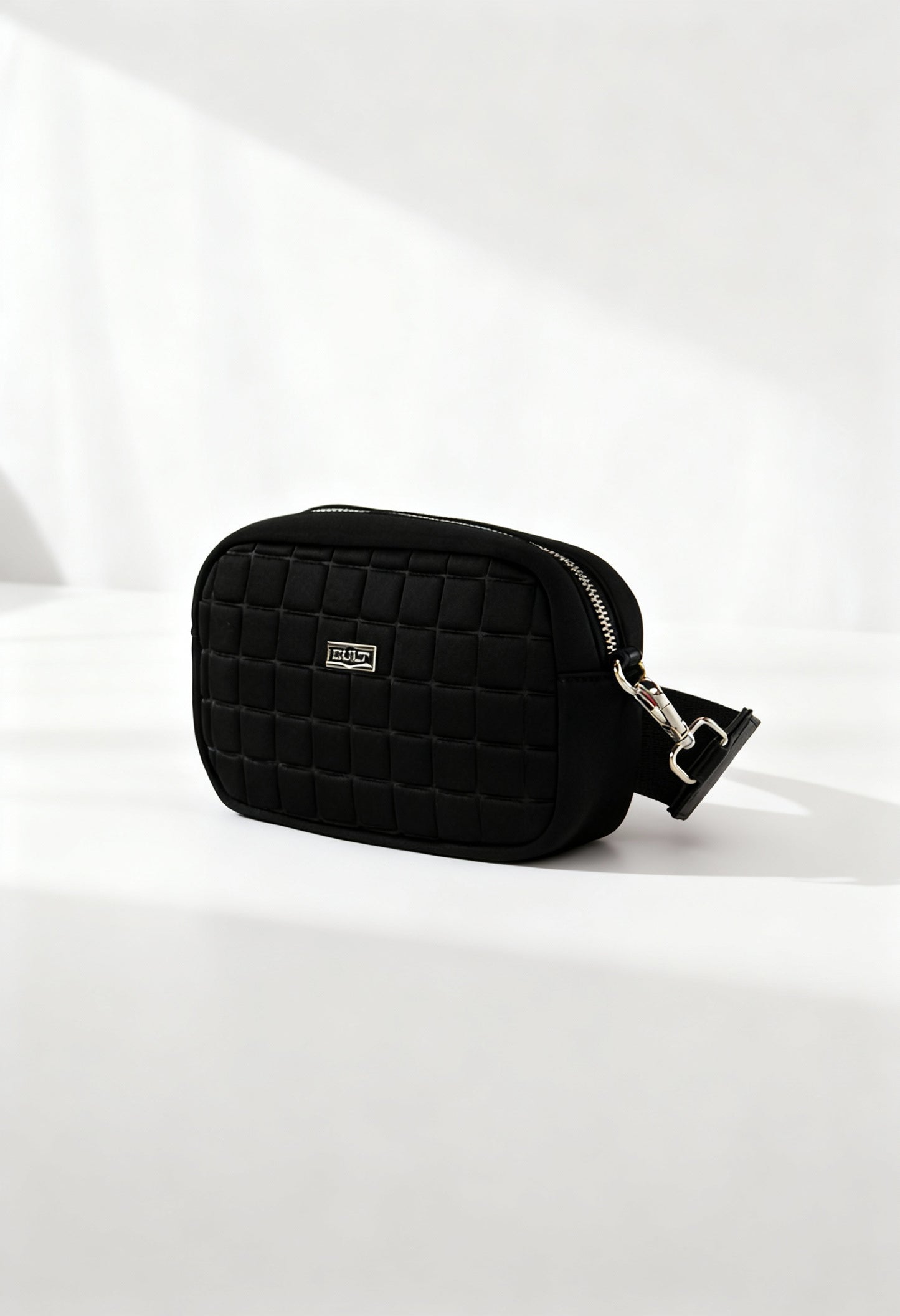 Front angle of the black Cult quilted across-body bag with zip closure and structured shape.