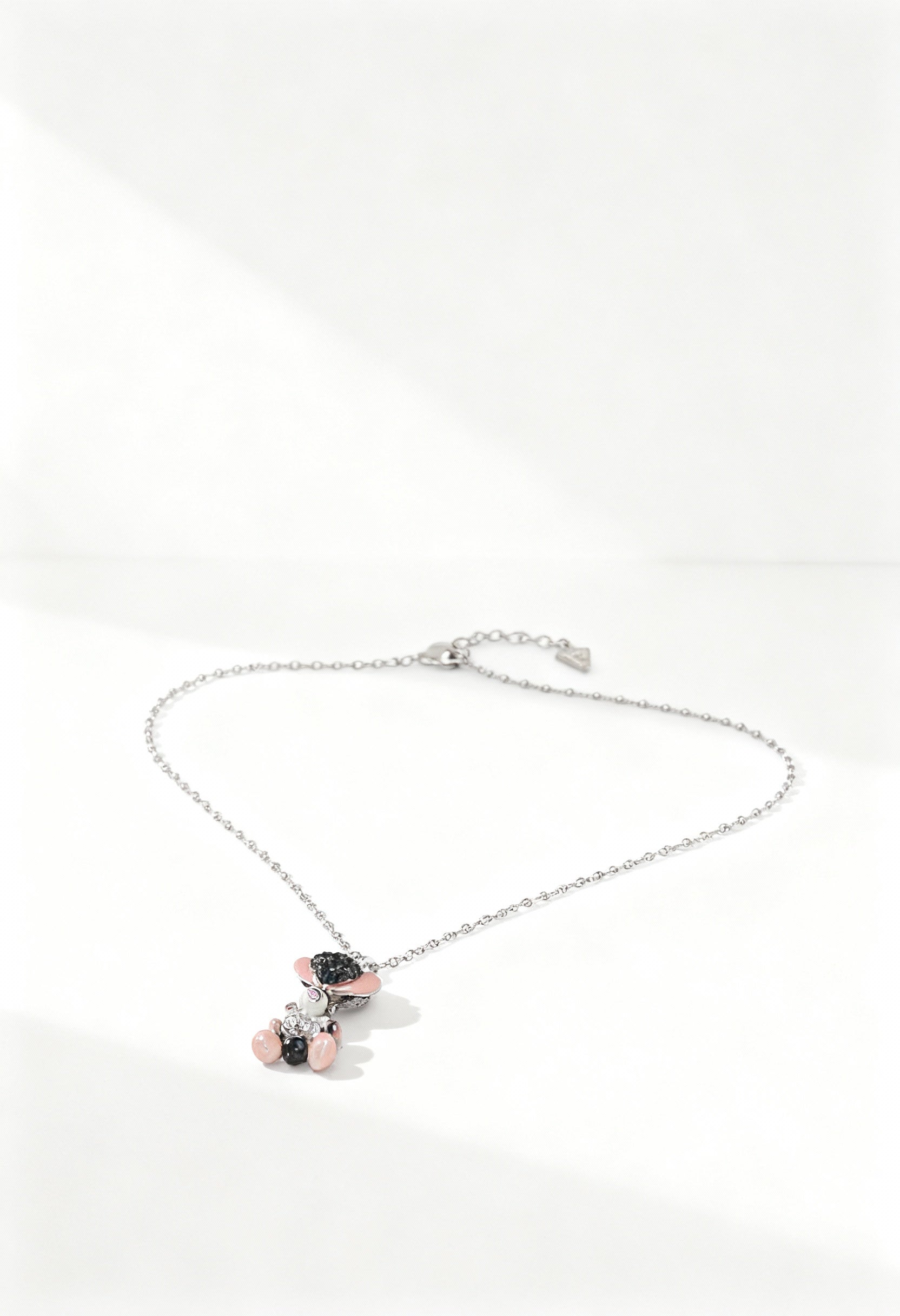 Front view of the Guess UBN120 steel necklace featuring a teddy bear pendant with pink and black appliqués.