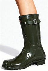 On-foot view of the dark green Hunter gloss rain boots with buckle detail and round toe.