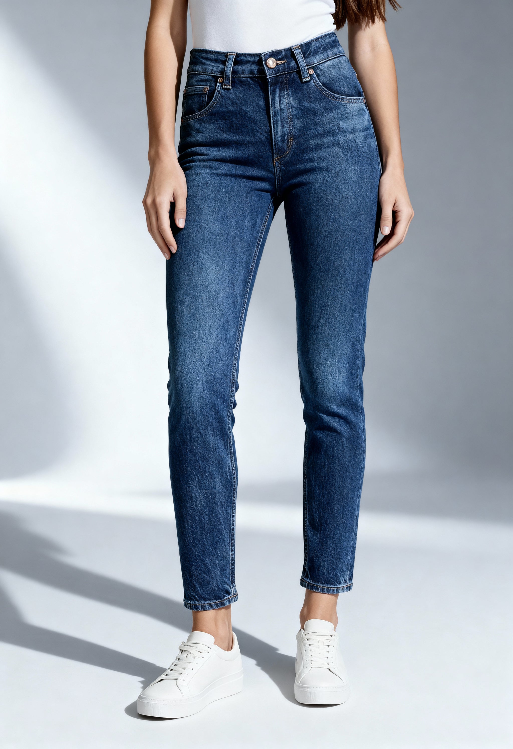 Front angled view of a woman wearing dark blue Lee 112346312 slim-fit jeans on a bright background.
