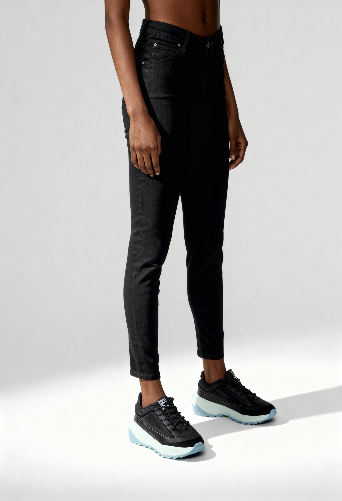 Front angled view of a woman wearing black Lee L526FS47 skinny jeans on a bright background.