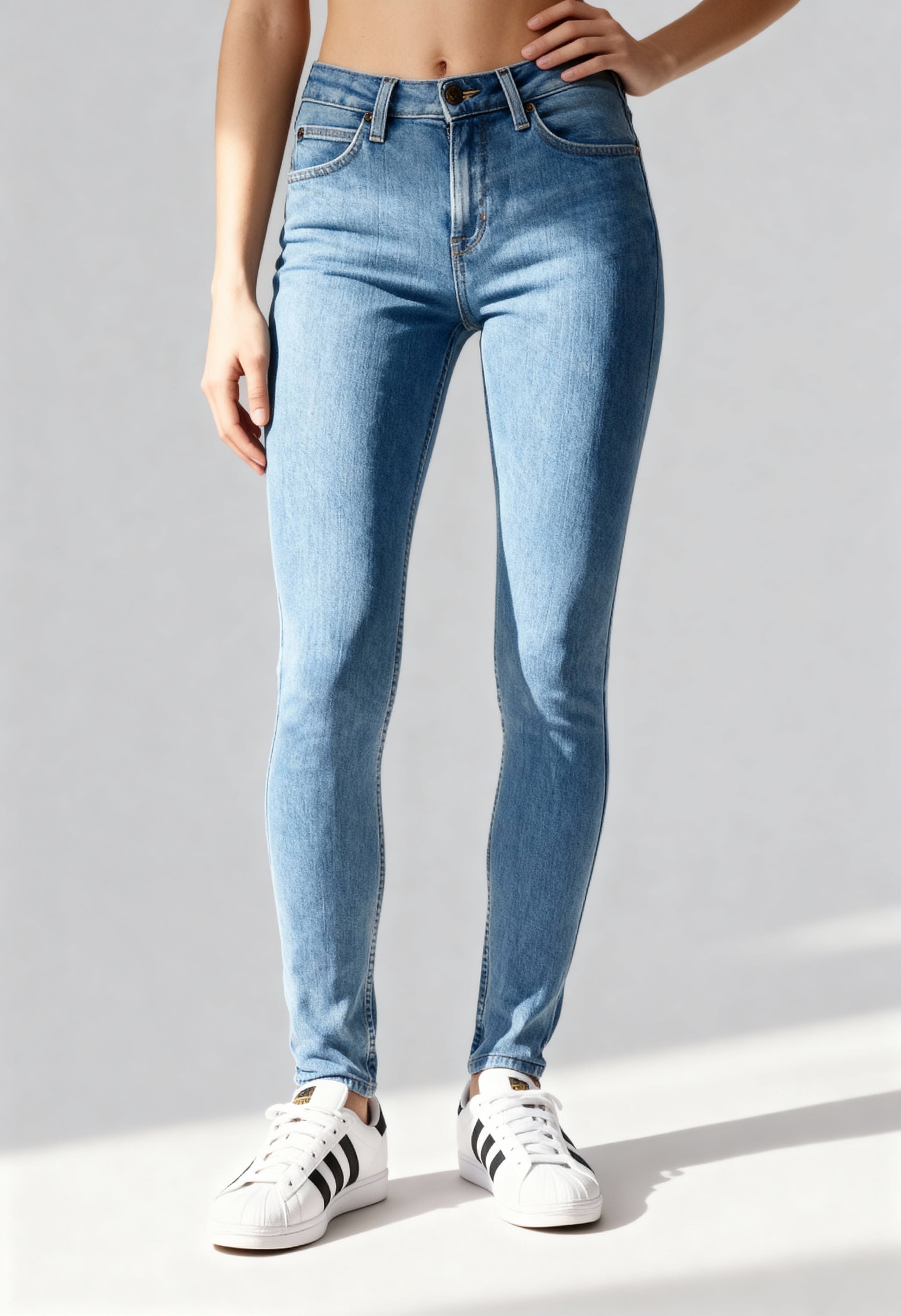 Front angled view of a woman wearing light blue Lee L626FAB38 skinny jeans on a bright background.