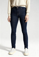 Front view of a woman wearing dark blue Lee L626MDNX skinny jeans on a light background.