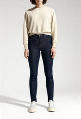 Full-length studio shot of a woman wearing dark blue Lee L626MDNX skinny jeans.
