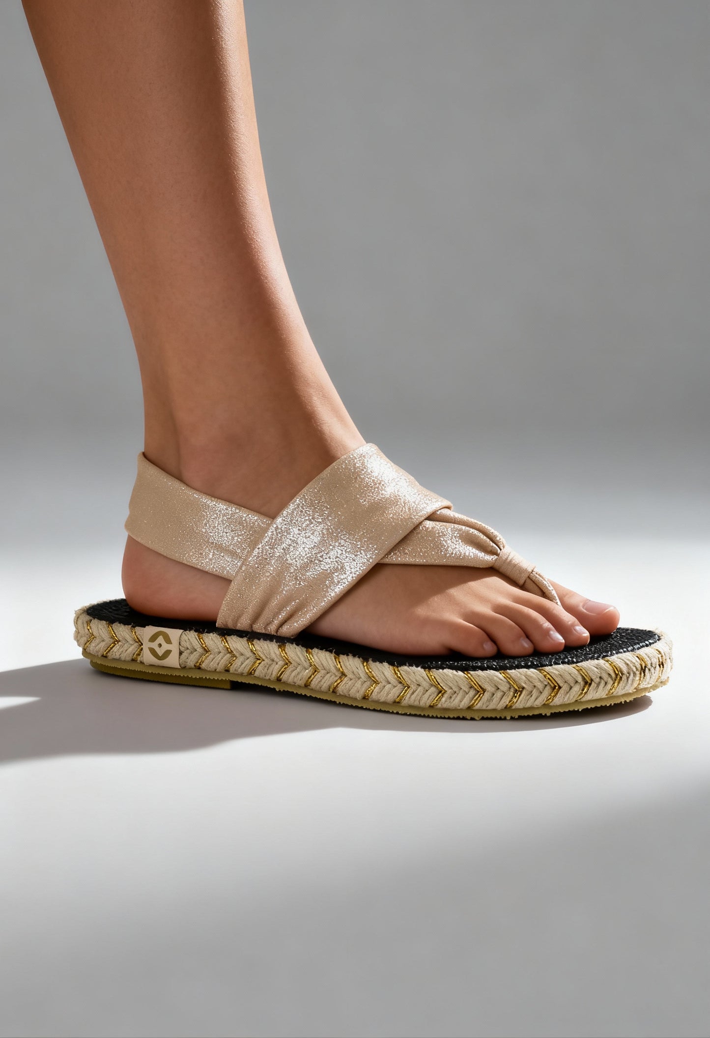 On-foot view of the beige Nalho fabric flip-flop sandals with braided sole and cross-strap design.