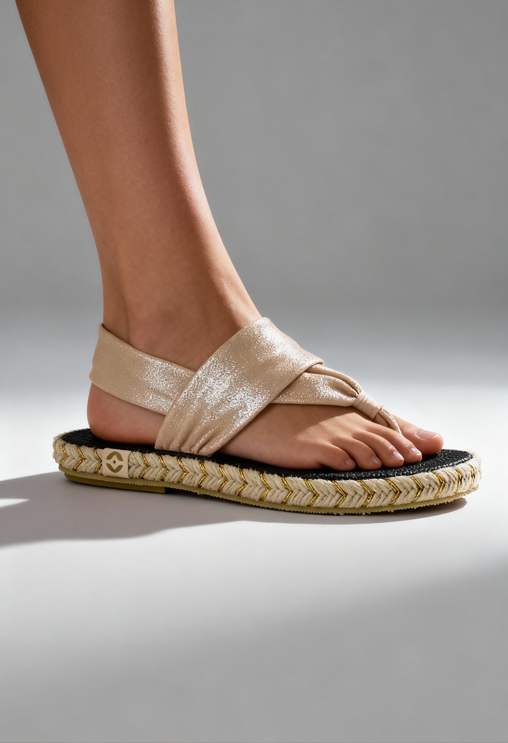 On-foot view of the beige Nalho fabric flip-flop sandals with braided sole and cross-strap design.