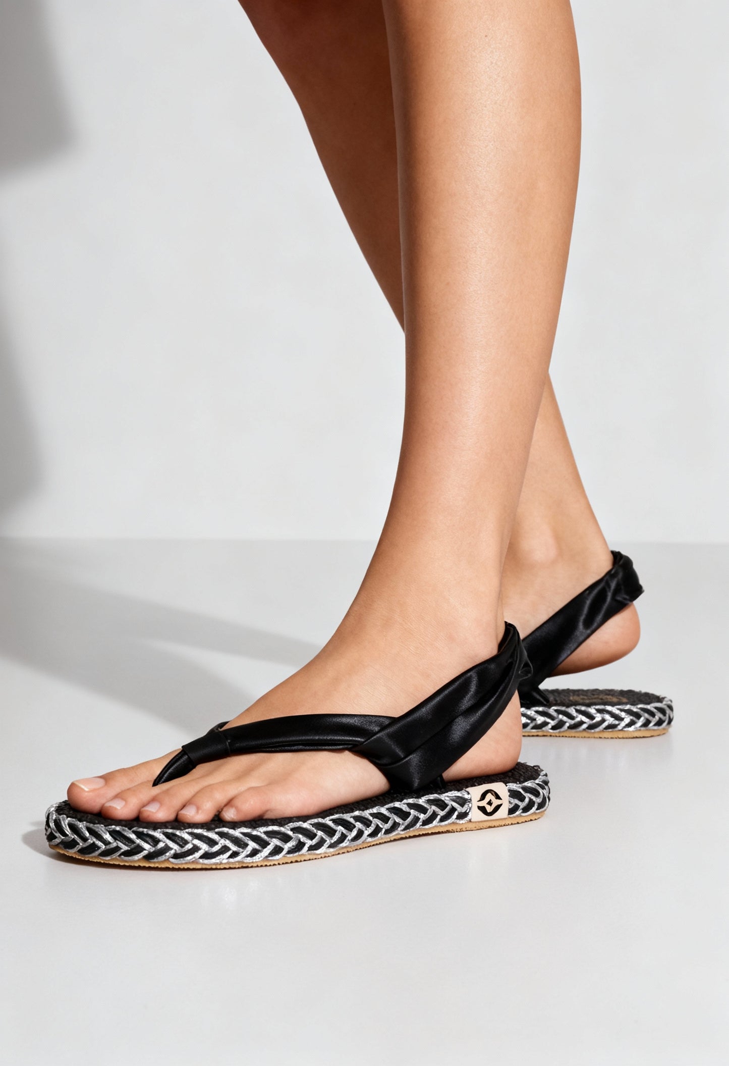 On-foot view of the black Nalho sling-back flip-flop sandals with braided sole and cushioned footbed.