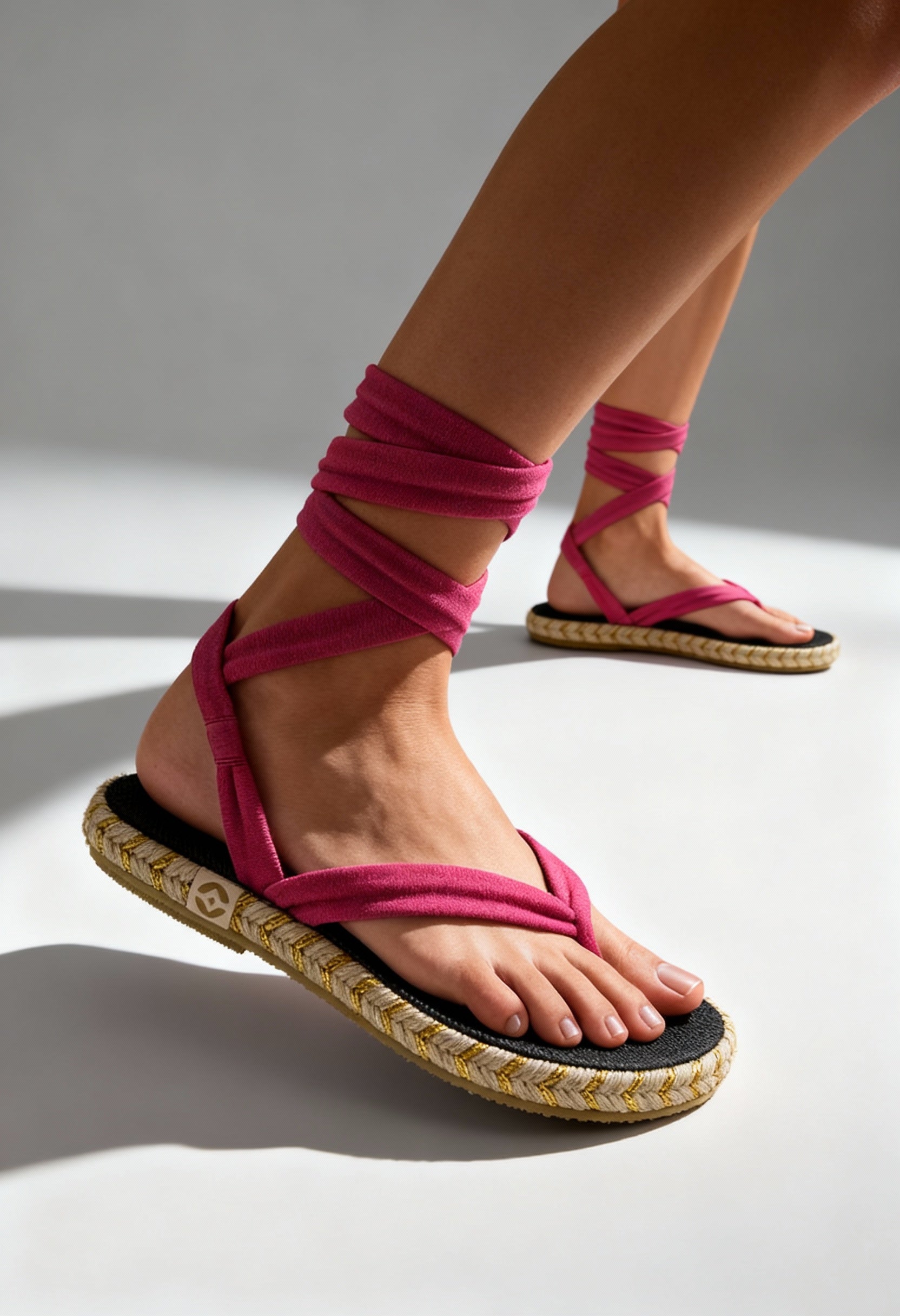On-foot view of the pink Nalho wrap-strap flip-flop sandals with braided sole and cushioned footbed.