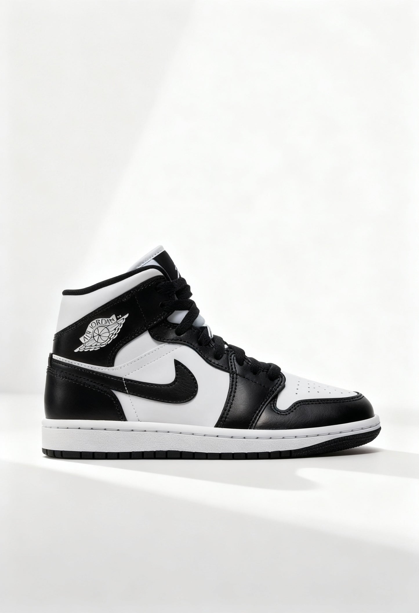 Brand new Nike Air Jordan 1 Mid women's sneakers in black and white side view.