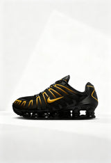 Brand new Nike Shox TL men's sneakers in black and gold side view.