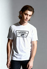 Front angled view of a man wearing the white Vans VN000QN8YB21 T-shirt on a light background.